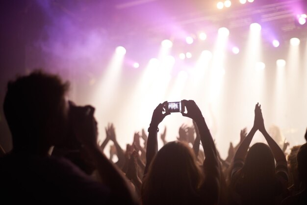 Scattare la band inquadratura posteriore di fan che filmano una band sul palco