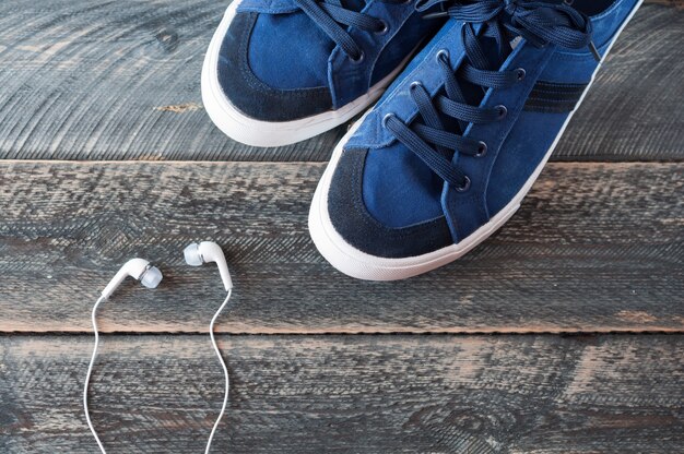 Sneakers and earphones on old wooden background