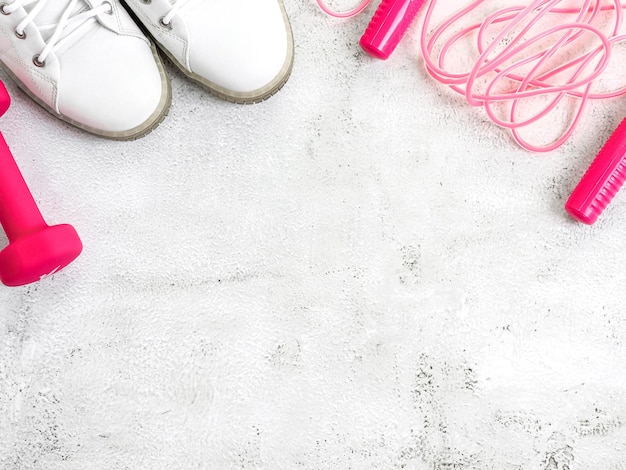 Sneakers and skipping rope on a concrete background