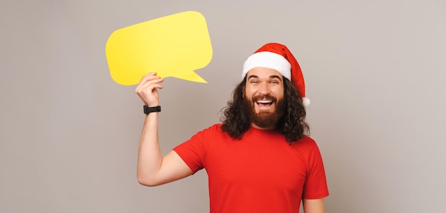 Sneaky bearded man is holding a yellow bubble speech on Christmas time