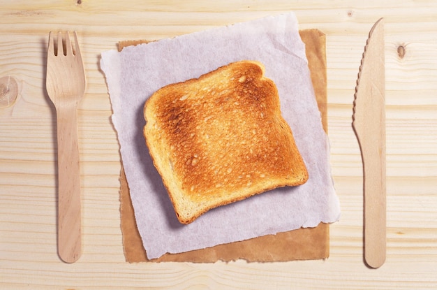 Sneetje geroosterd brood en houten bestek op tafelblad weergave