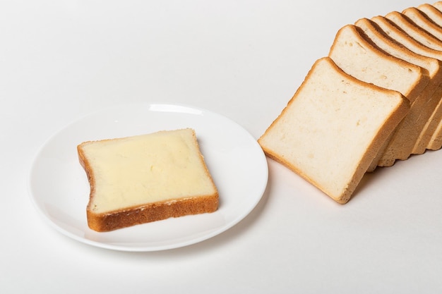 Sneetje tarwebrood besmeerd met boter Wit vierkant vers yukonbrood op een witte achtergrond