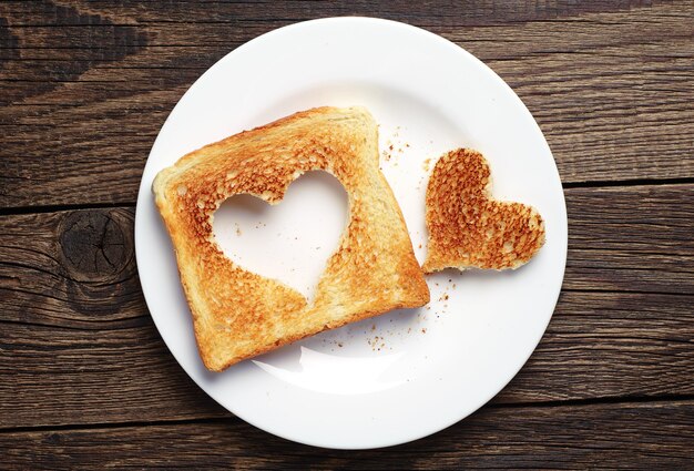 Sneetje toast brood met uitgesneden hartvorm op vintage houten achtergrond