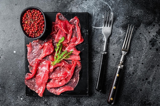 Sneetjes Beef Capriccio rauw gemarmerd vlees Zwarte achtergrond Bovenaanzicht