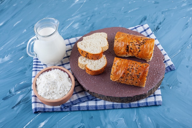 Sneetjes brood op een bord naast een gekookt ei en een kom met bloem op een handdoek, op het blauwe oppervlak.