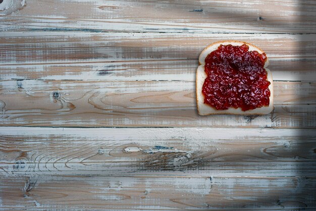 Sneetjes brood sandwich met aardbeienjam op oude houten tafel