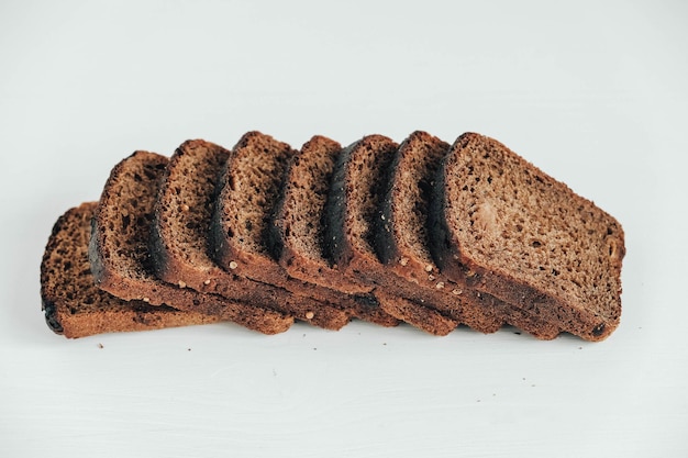 Sneetjes vers bruin brood met rozijnen op een witte houten achtergrond. Kopiëren, lege ruimte voor tekst