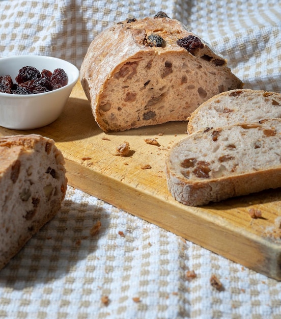 Sneetjes zelfgebakken brood met rozijnen, walnoten, kruiden en gehakte noten op beige en wit tafelkleed