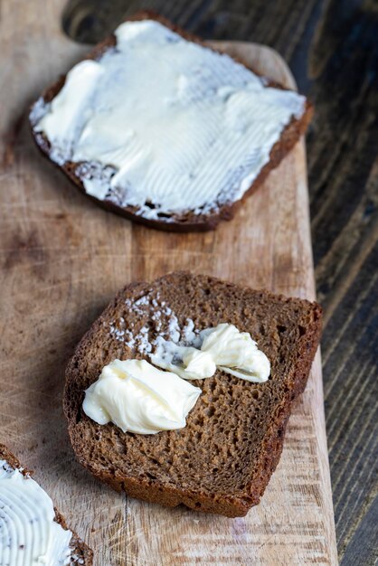 Sneetjes zwart gesneden brood met roomboter van melk