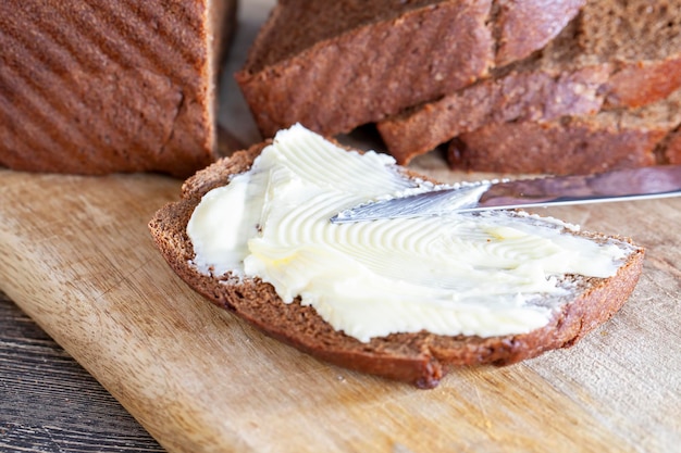 Sneetjes zwart gesneden brood met roomboter van melk