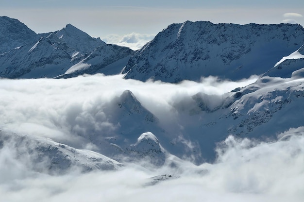 Sneeuw bedekte hoge bergen mist en wolken stijgen van boven