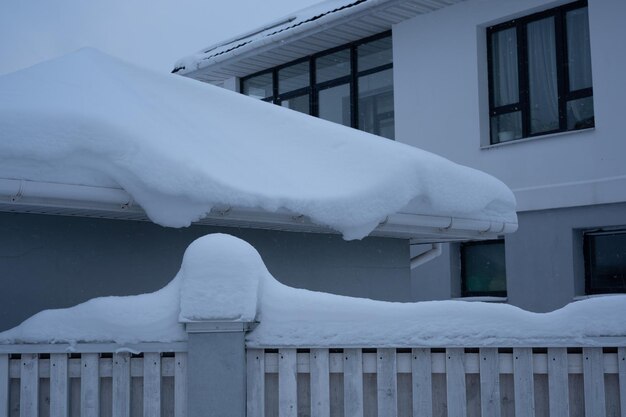 Sneeuw die omheining en huis bedekt