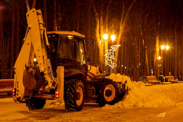 Sneeuw in het park in de winter schoonmaken met een tractor in de avond