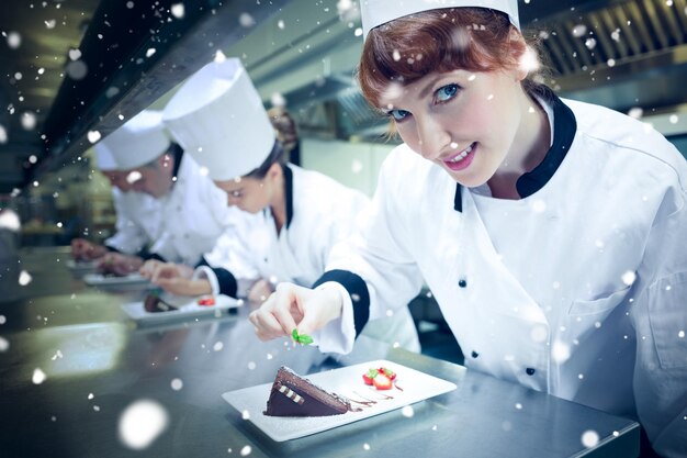 Sneeuw tegen glimlachende chef-kok die dessertbord versiert
