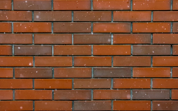 Sneeuw vliegt op de achtergrond van een rode bakstenen muur achtergrond