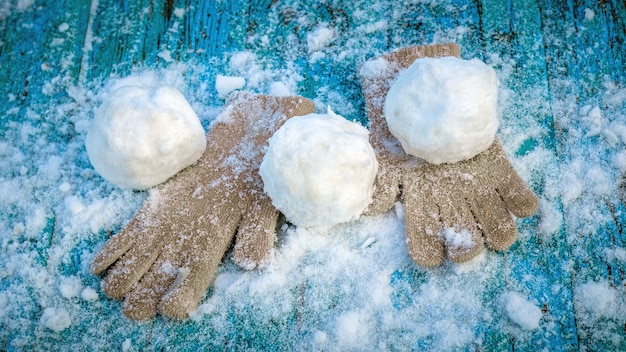 Sneeuwballen en wanten op een besneeuwde houten ondergrond