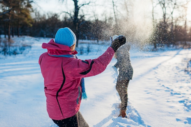 Sneeuwballen spelen in winter woud. Familiemoeder en dochter die pret hebben die sneeuw in openlucht werpen