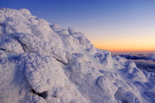 Sneeuwbedekt landschap tegen de hemel bij zonsondergang