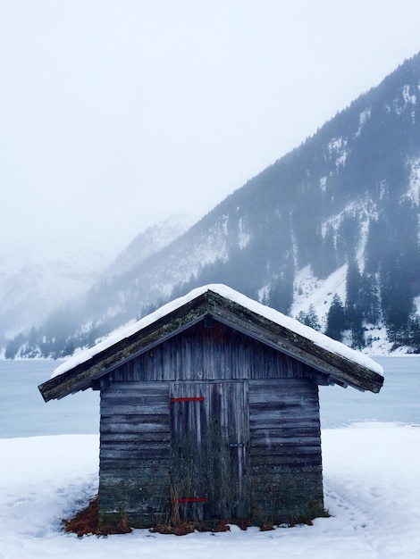 Sneeuwbedekte hut aan wal bij mistig weer