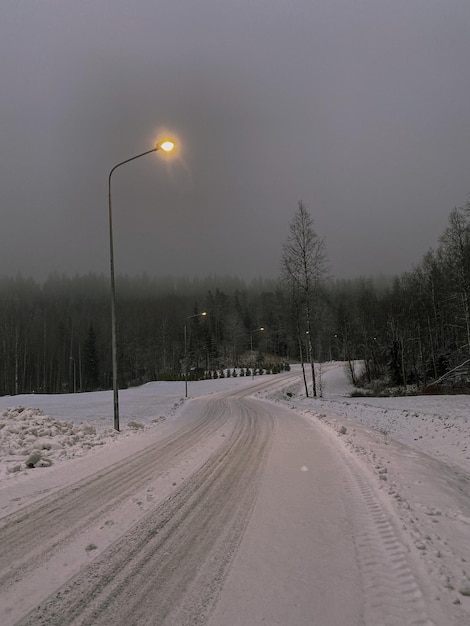 Sneeuwbedekte weg met bomen tegen de lucht tijdens de winter