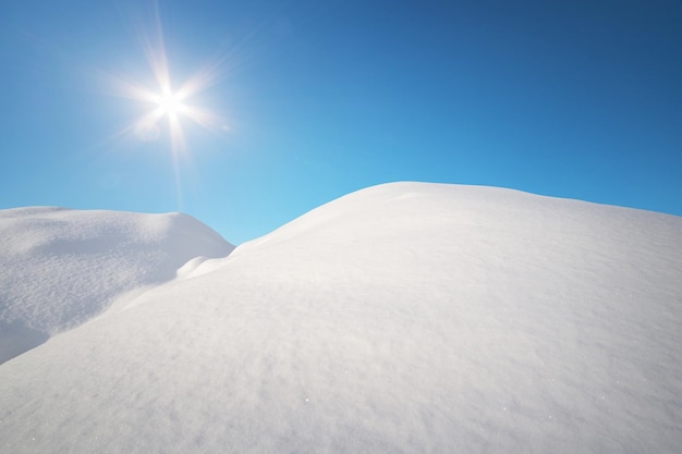 Sneeuwheuvels en diepblauwe zonnige hemel