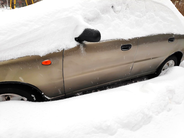 Sneeuwlaag op de voorruit van de sedan op de oprit van de straat in de stad parkeerplaats ter plaatse auto vast na zware sneeuwstorm sneeuwval sneeuwstorm in de winter sneeuwbanken en voertuig in extreme weersomstandigheden