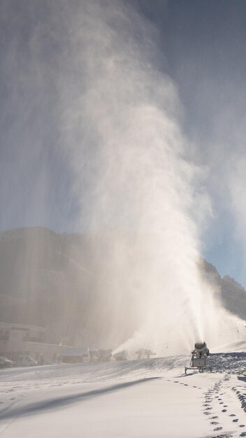Sneeuwmachine, sneeuwkanon of -geweer in actie op een zonnige winterdag in het skigebied Kranjska Gora.
