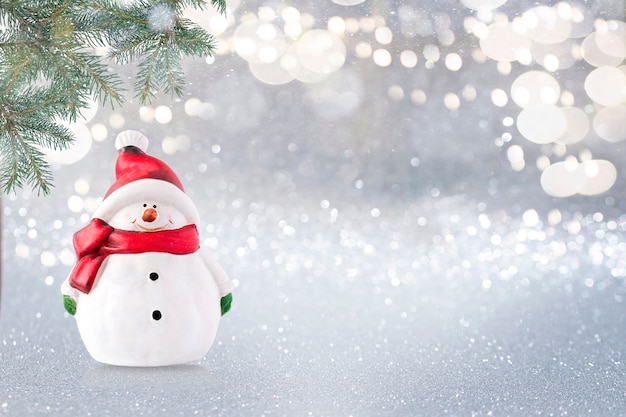 Sneeuwpop op glitterachtergrond met dennentak in een hoek en kopieer ruimte