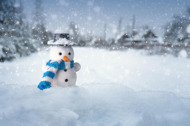 Sneeuwpop staat in een sneeuwjacht met een dorp op de achtergrond in een besneeuwde avond