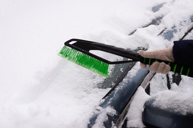 Sneeuwruimen, auto in de sneeuw. Vrouw reinigt de auto van sneeuw.