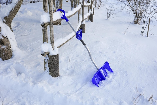 Sneeuwruimen bij de houten omheiningsschop in de sneeuw