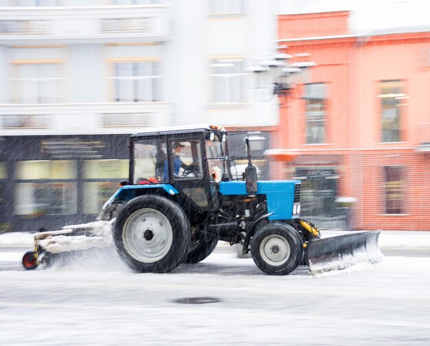 Sneeuwruimmachine die de straat van sneeuw schoonmaakt. Sneeuwploegvrachtwagen die sneeuw op straat na blizzard verwijdert. Opzettelijke bewegingsonscherpte