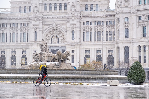 Sneeuwstorm "Filomena" in de binnenstad van Madrid op La Plaza De Cibeles en een bezorger die het plein overstak