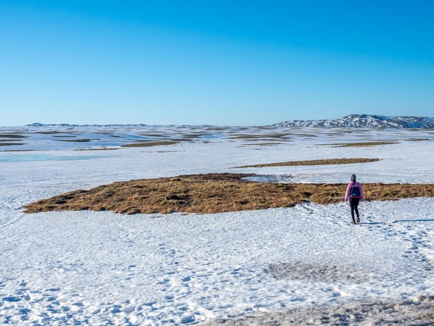 Sneeuwveld met bergen onder heldere blauwe hemel in landelijk gebied van IJsland