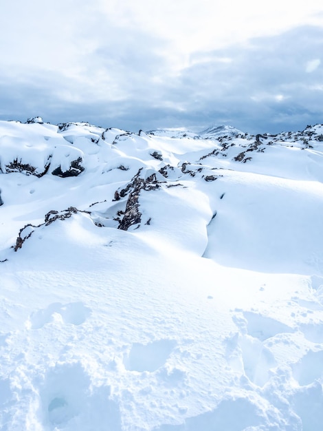 Sneeuwveld met witte bergen onder bewolkte hemel in IJsland