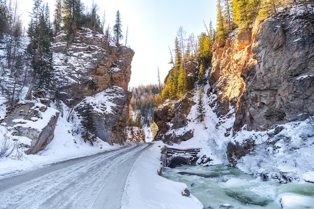 Sneeuwweg in de bergen dichtbij rivier in het Altai-gebergte. Rode poort