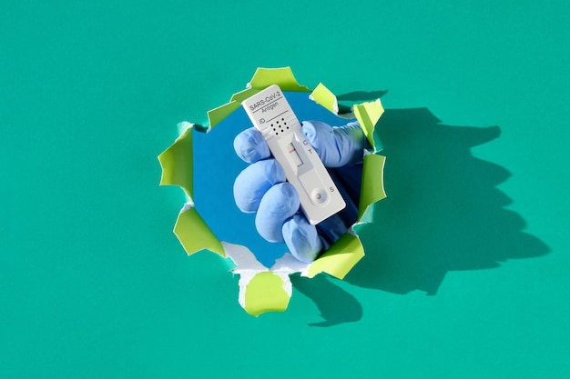Snelle covid-test in hand in handschoen door hand met papiergaatje met snelle antilichaamdetectietest