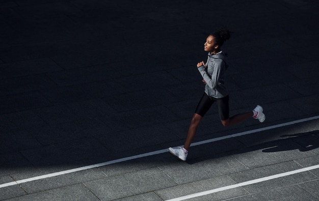 Snelle loper Jonge Afro-Amerikaanse vrouw in sportieve kleding traint overdag buiten