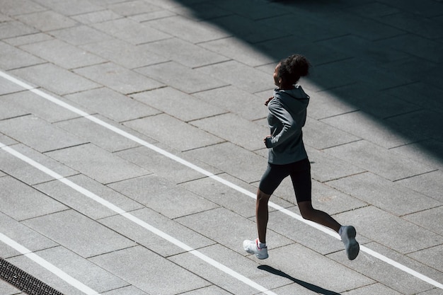 Snelle loper Jonge afro-amerikaanse vrouw in sportieve kleding traint overdag buiten