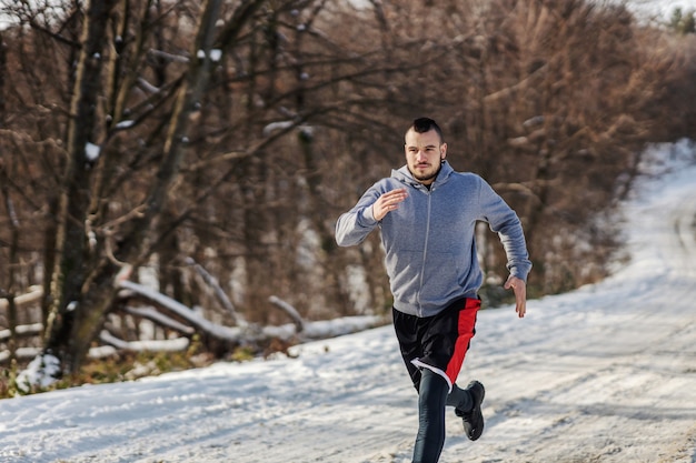 Snelle sportman sprinten in het bos op besneeuwde winterdag, cardio-oefeningen, winterfitness