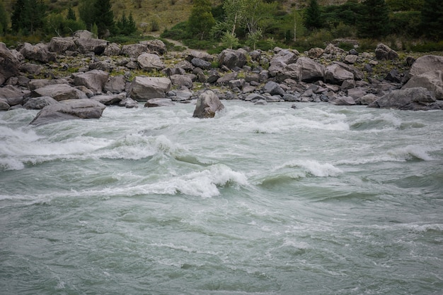 Foto snelle stroming van water in bergrivier op de achtergrond van rotsachtige oevers, gebied om te raften, hoge moeilijkheidsgraad.