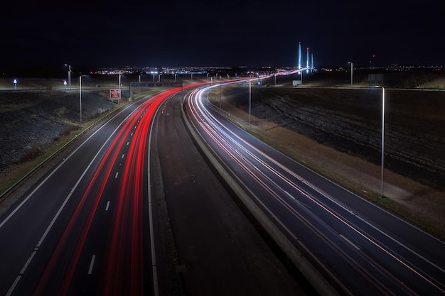 Snelweg die leidt naar de grote brug en 's nachts lichten van auto's