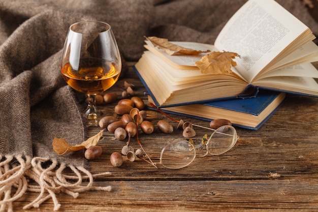 Snifter of brandy and book, dried oak leaves