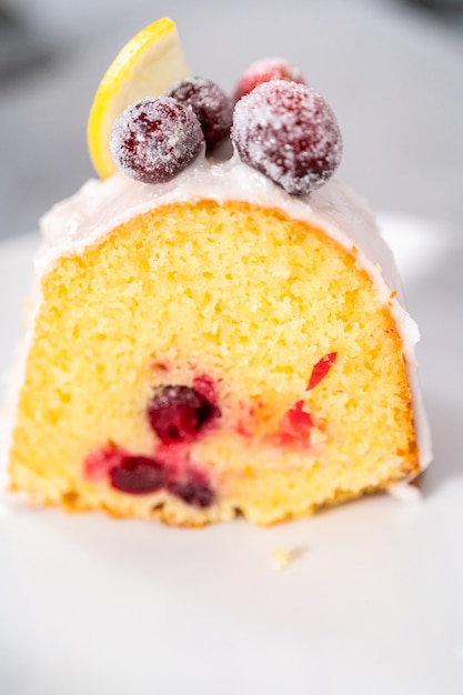 Snijd de citroen cranberry bundt cake op een wit bord.