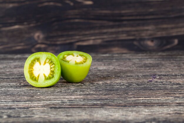 Snijd groene tomaat op een zwarte tafel, close-up van een groente