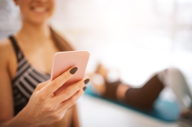 Snijd het beeld van de vrolijke jonge vrouw die de telefoon in de hand houdt en glimlacht