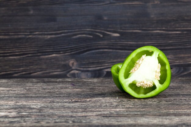 Snijd in een halve peper groen, close-up op een zwart bord met een zwarte muur, keukenhoek