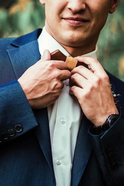 Snijd lachende man in elegante blauwe jas en licht geruite broek die bruine houten boog rechtmaakt