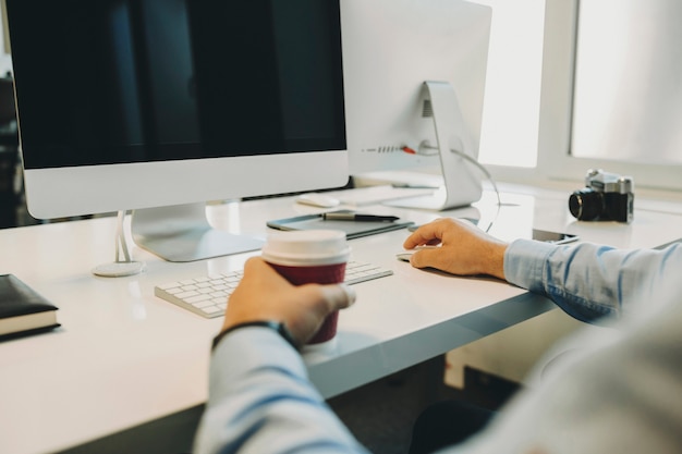 Snijd man met kopje koffie en zittend op de moderne computer op kantoor