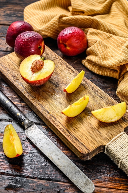 Snijd nectarines op een houten snijplank. Houten achtergrond. Bovenaanzicht.